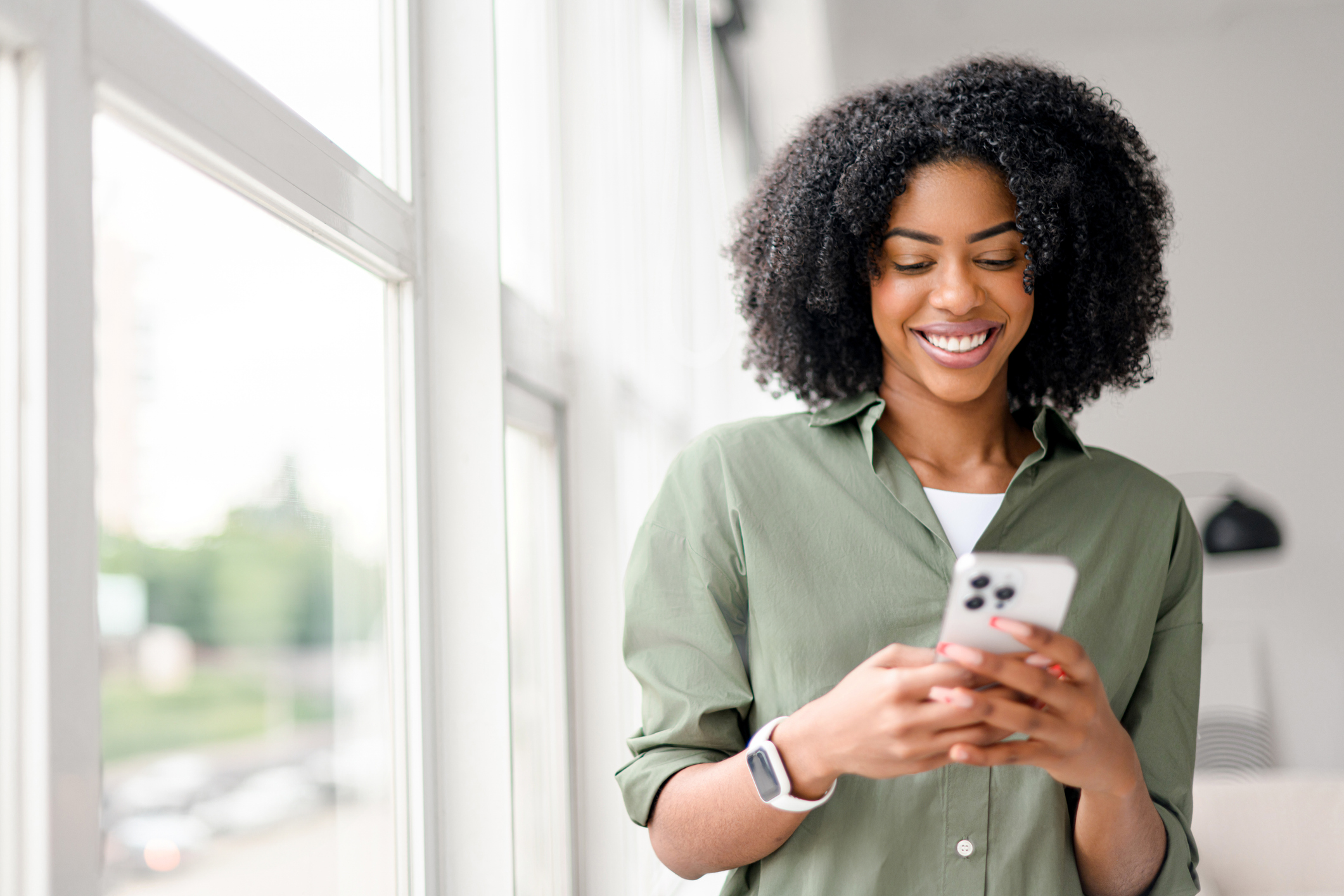 An African-American woman with a contagious smile interacts with her smartphone